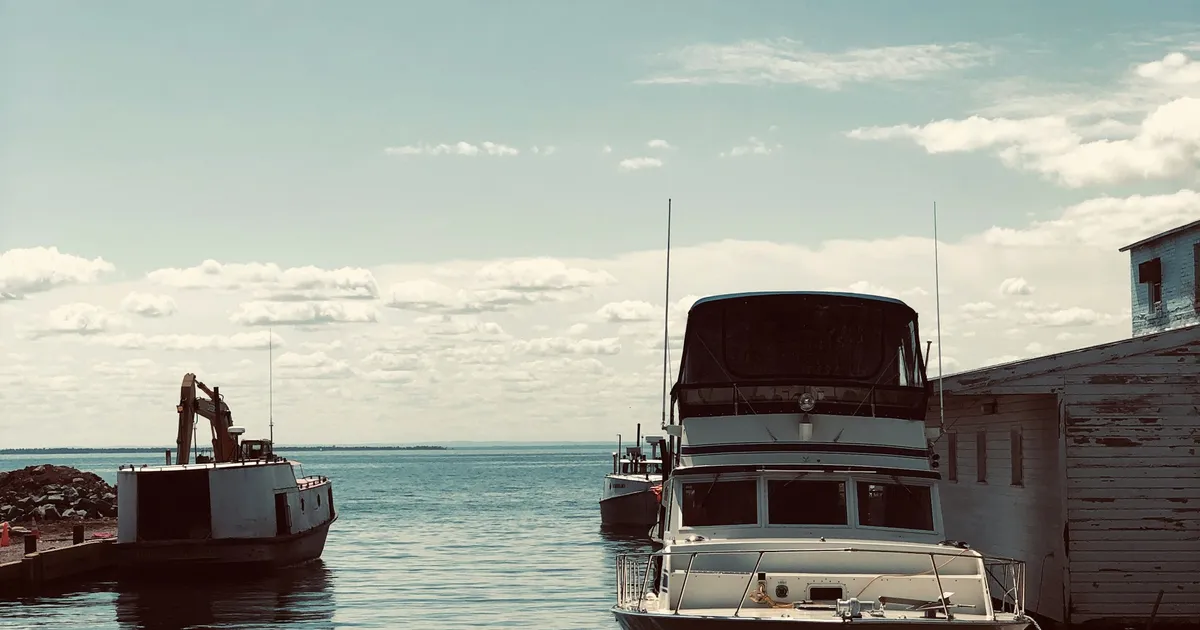 A family motorboat cruising on a clear Ontario lake with a forested shoreline in the background