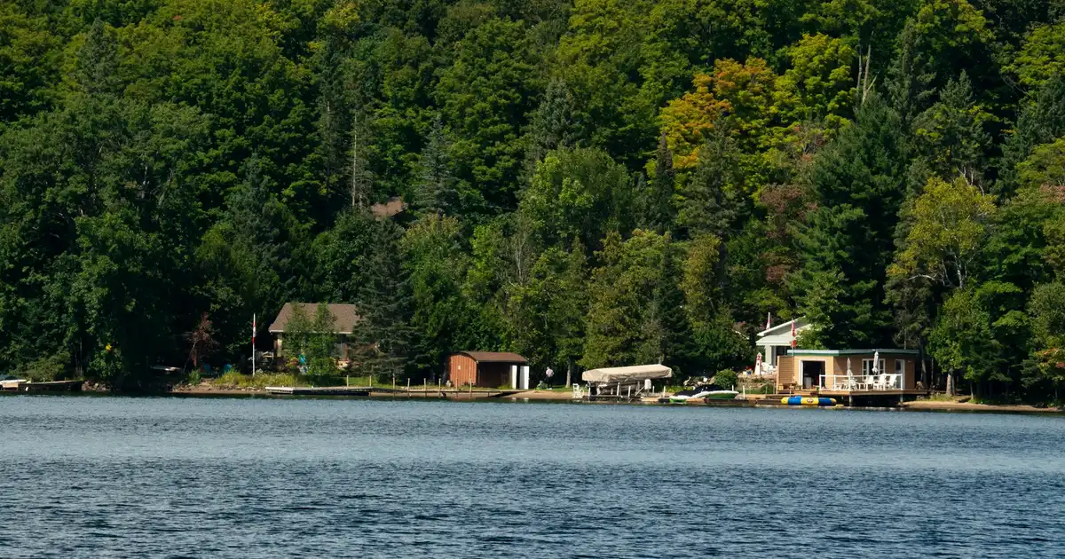 A couple standing on the dock of an Ontario cottage property they are considering purchasing on a clear summer day