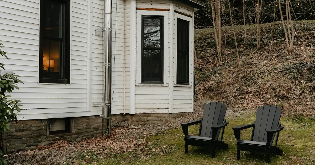 A cottage owner inspecting the exterior of a lakeside Ontario cottage on a sunny spring morning after snow melt